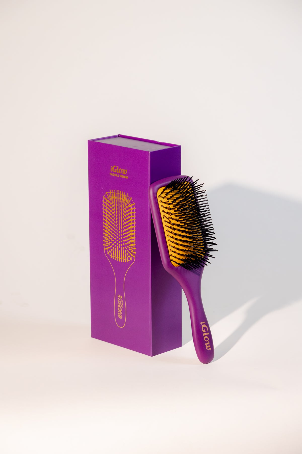 iGlow Paddle Brush ved siden av den lilla produktesken