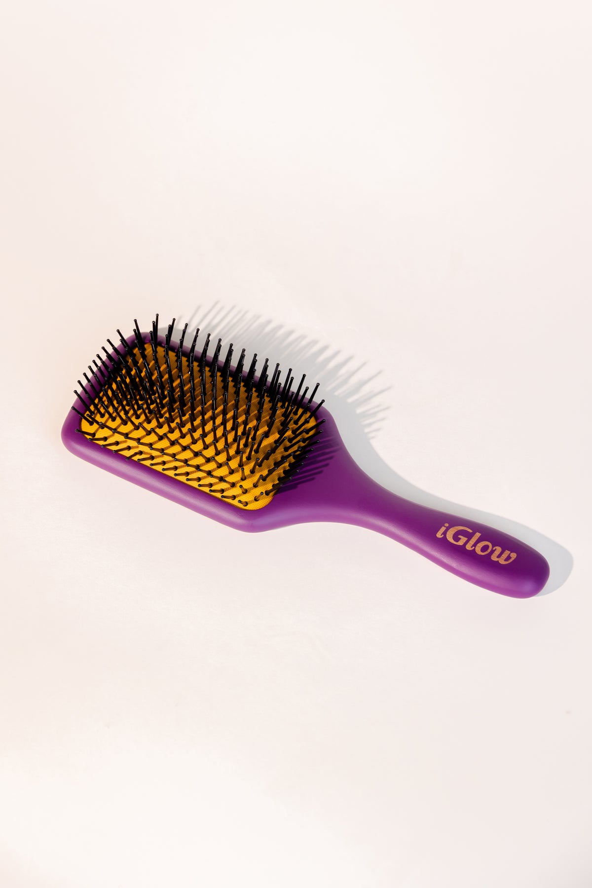 iGlow Paddle Brush i lilla og gult, sett skrått forfra