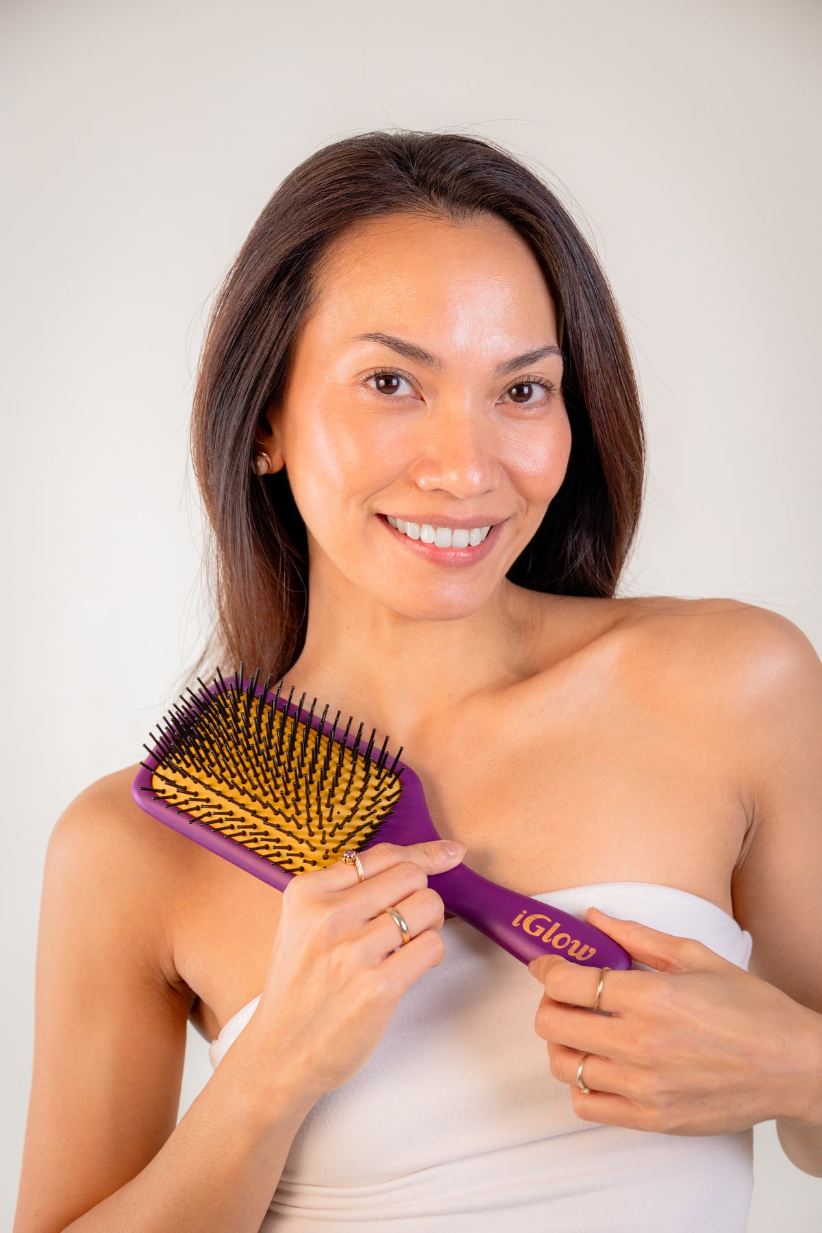 Modell holder iGlow Paddle Brush slik at børsteflate og håndtak vises